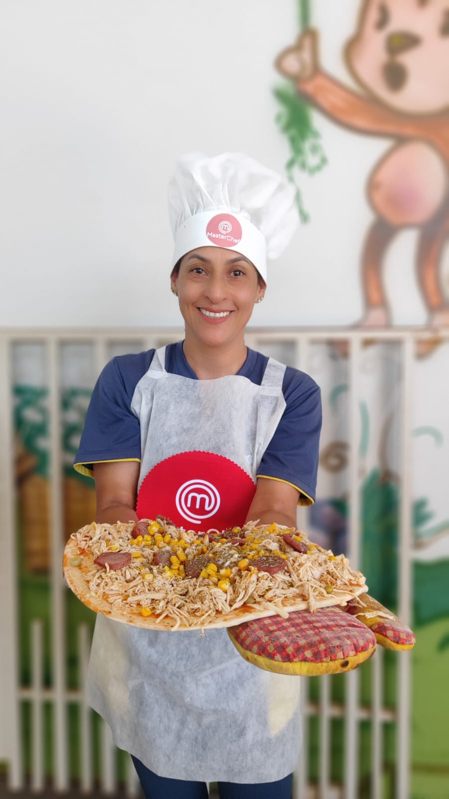 Professora mostrando uma pizza feita na cozinha experimental