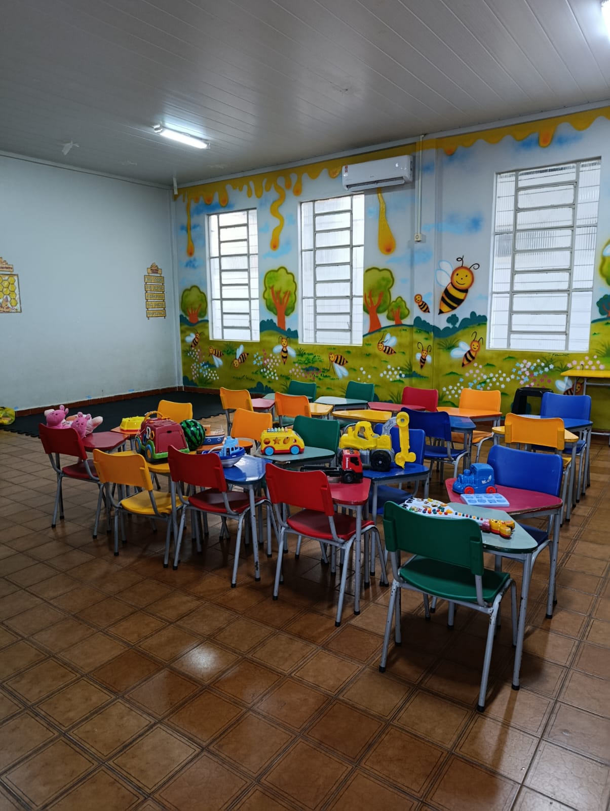Sala de aula colorida com mesinhas e cadeiras infantis